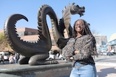 woman outside posing in front of Drexel Dragon statue 